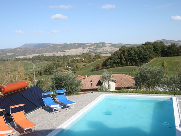 A swimming pool with lounge chairs, a small building, and a view of rolling hills and trees. - Timeless Villa in Cagli With Garden and Swimming Pool (Cagli)