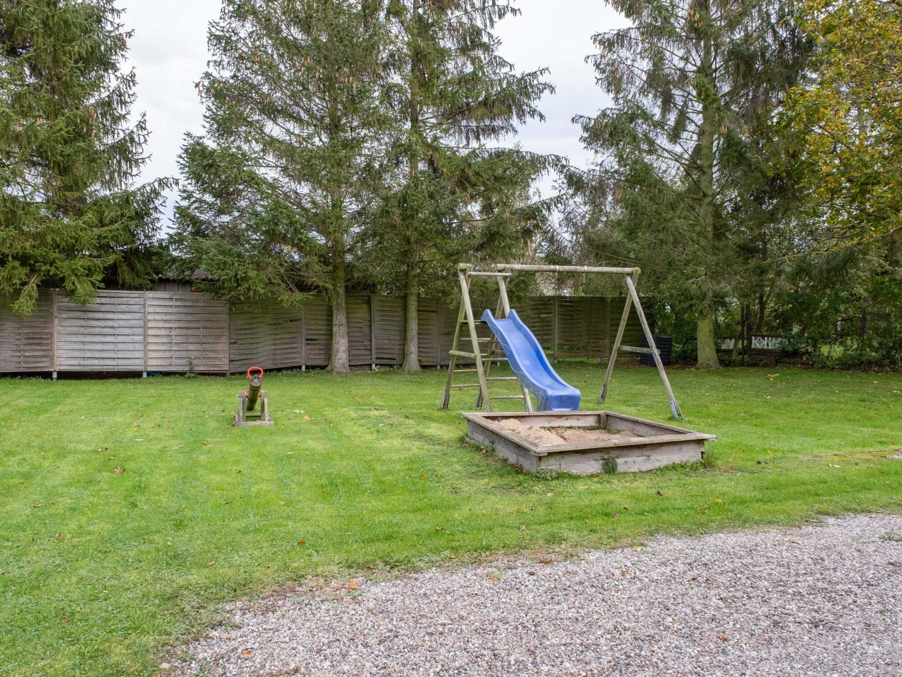 A backyard with a wooden swing set and a blue slide.