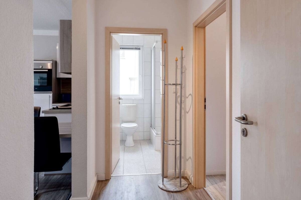 Ein schmaler Gang führt zu einem Badezimmer mit Toilette und Fenster.