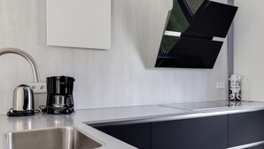 Eine moderne Küche mit integriertem Spülbecken, einer Kaffeemaschine und einem flachbildfernseher an der Wand.