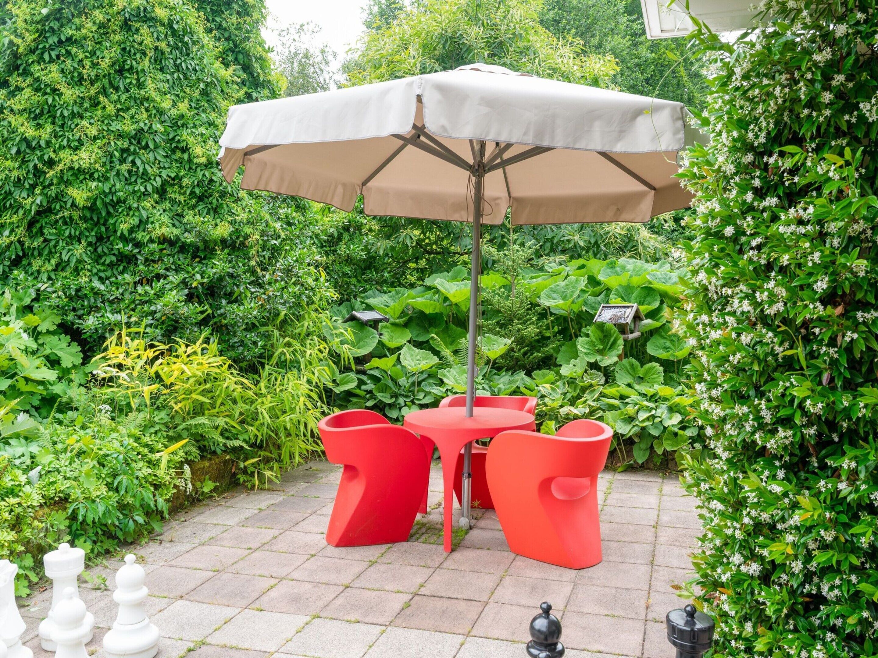 A patio with a table and chairs, surrounded by lush greenery.