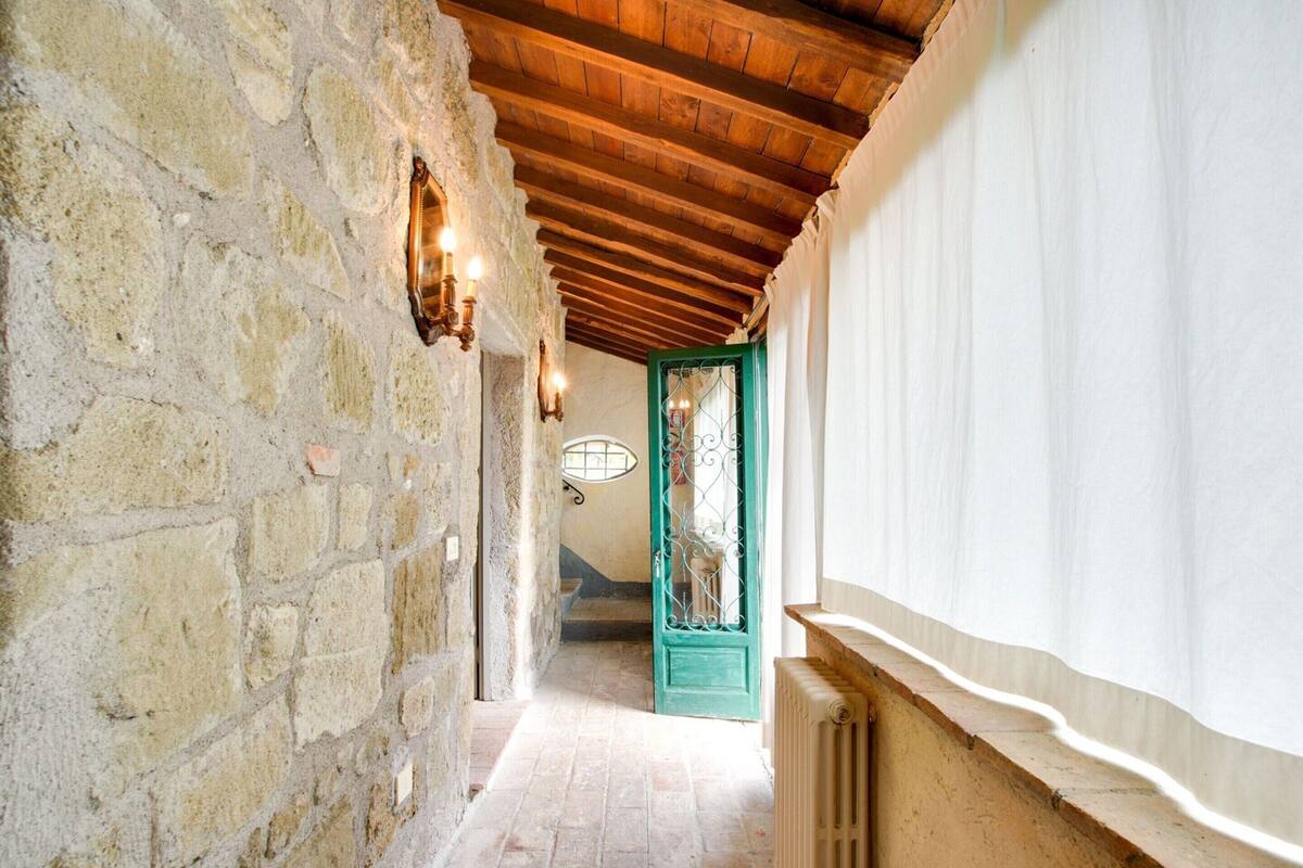 A narrow hallway with stone walls, wooden beams, and a radiator.