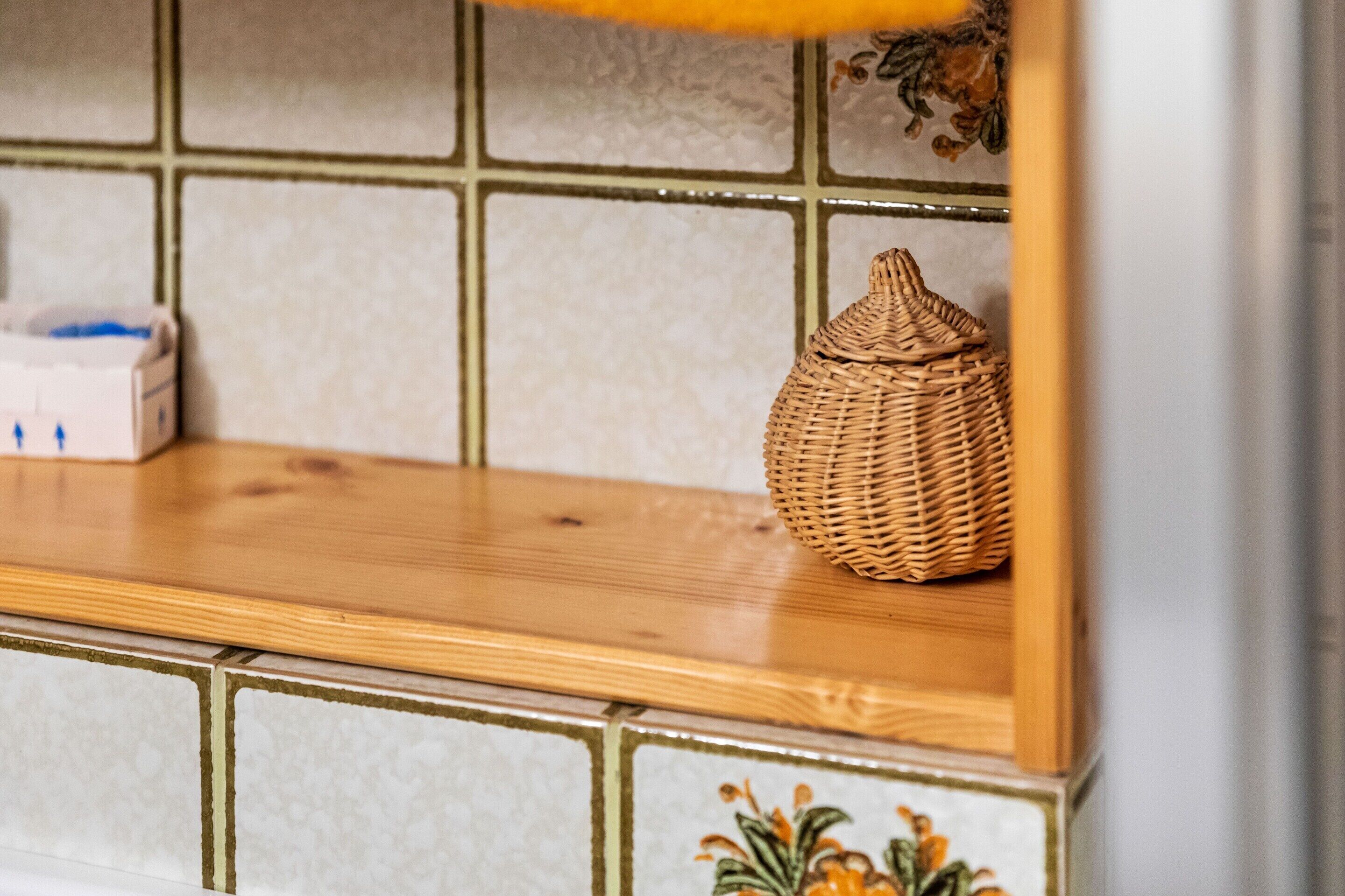 A wooden shelf with a woven basket and a tissue box.