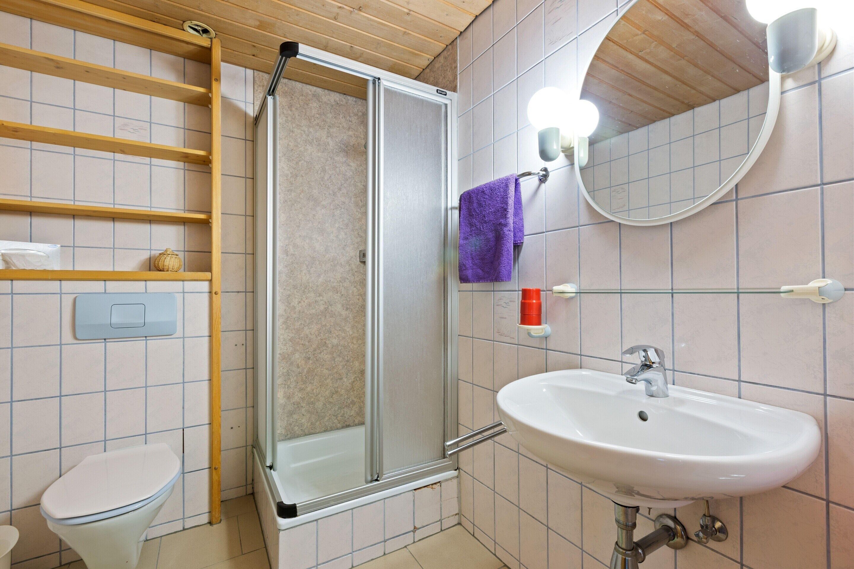Et badeværelse med bruser, toilet og vask.