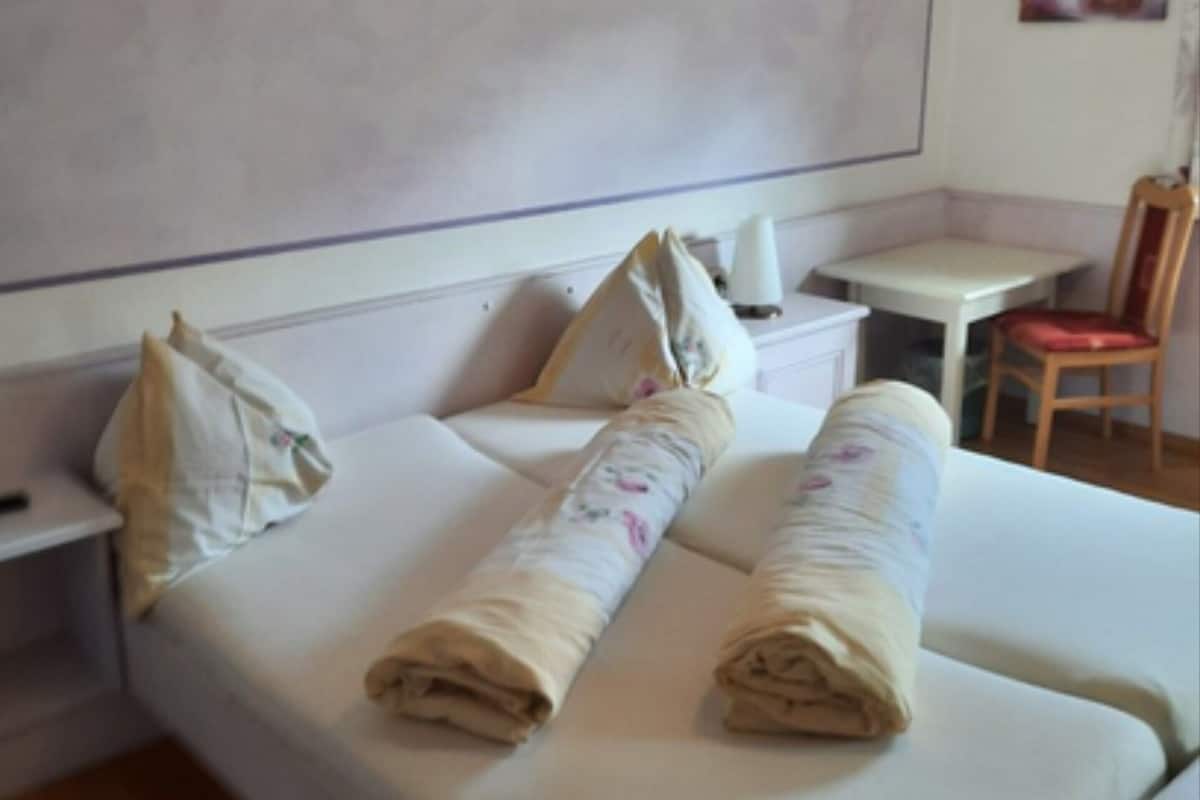 A hotel room with a bed, a bedside table, a chair, and a small table.