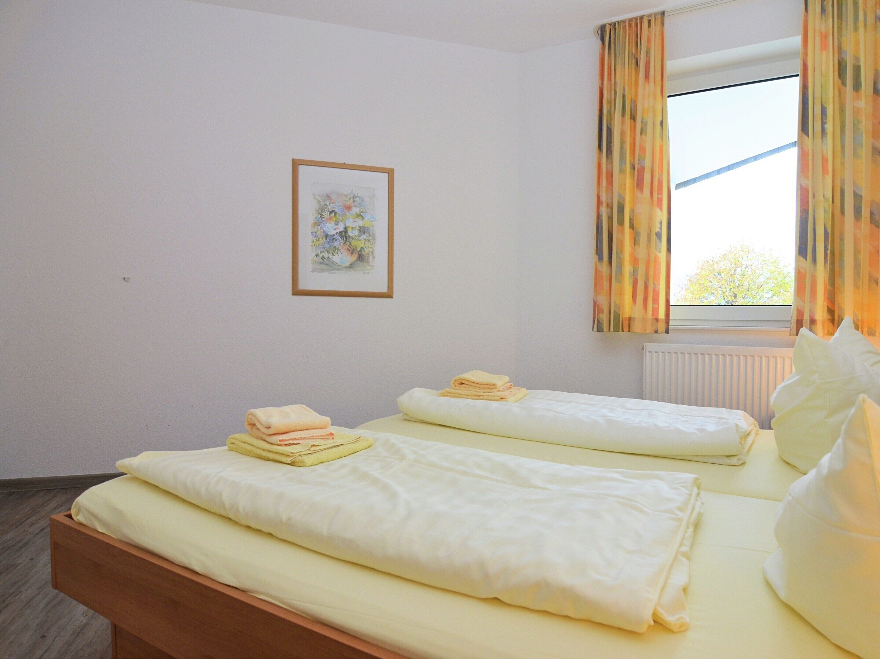 A hotel room with two beds, a framed picture on the wall, and a window with curtains.
