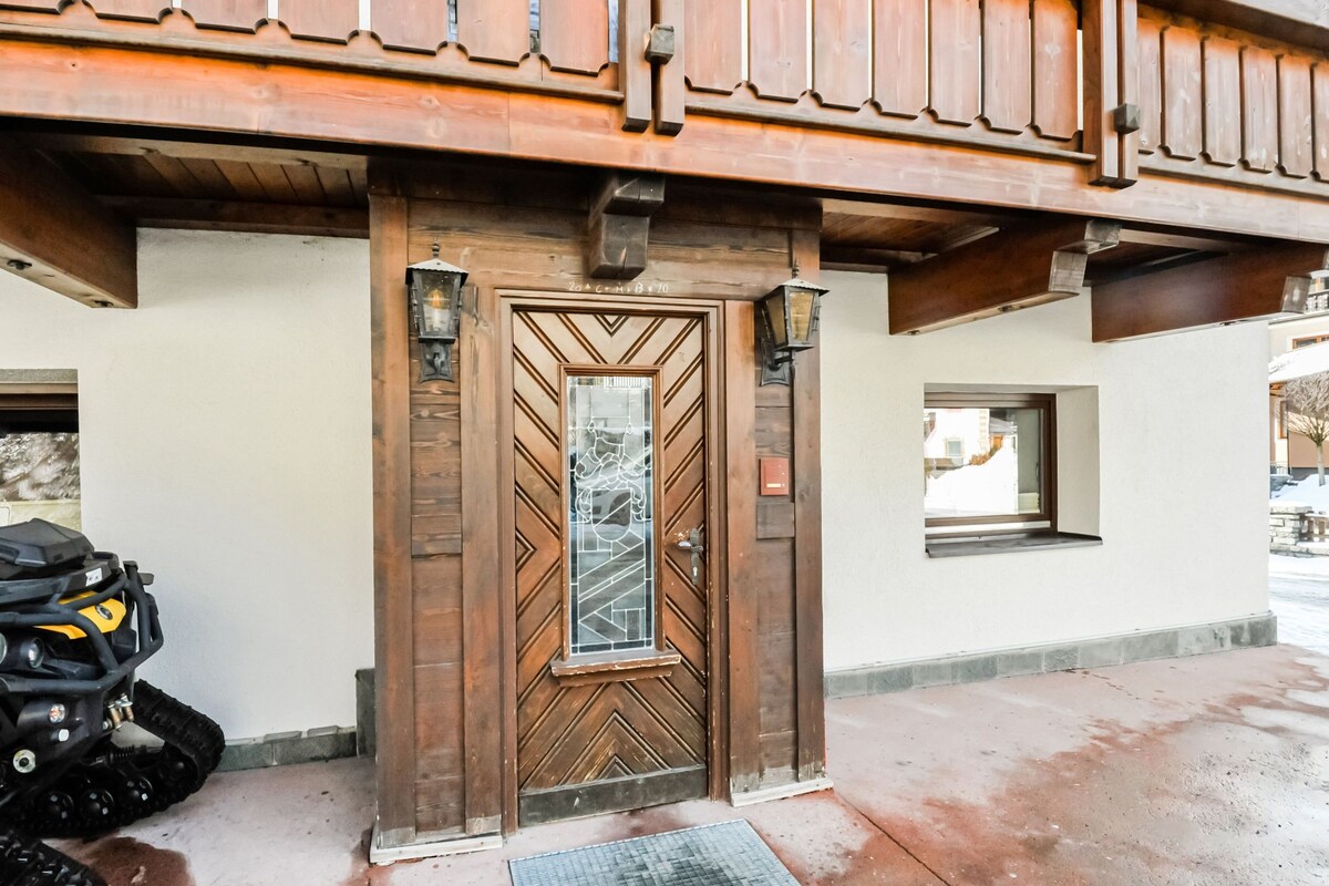 A wooden door with a geometric pattern, a small window, and a motorcycle parked outside.