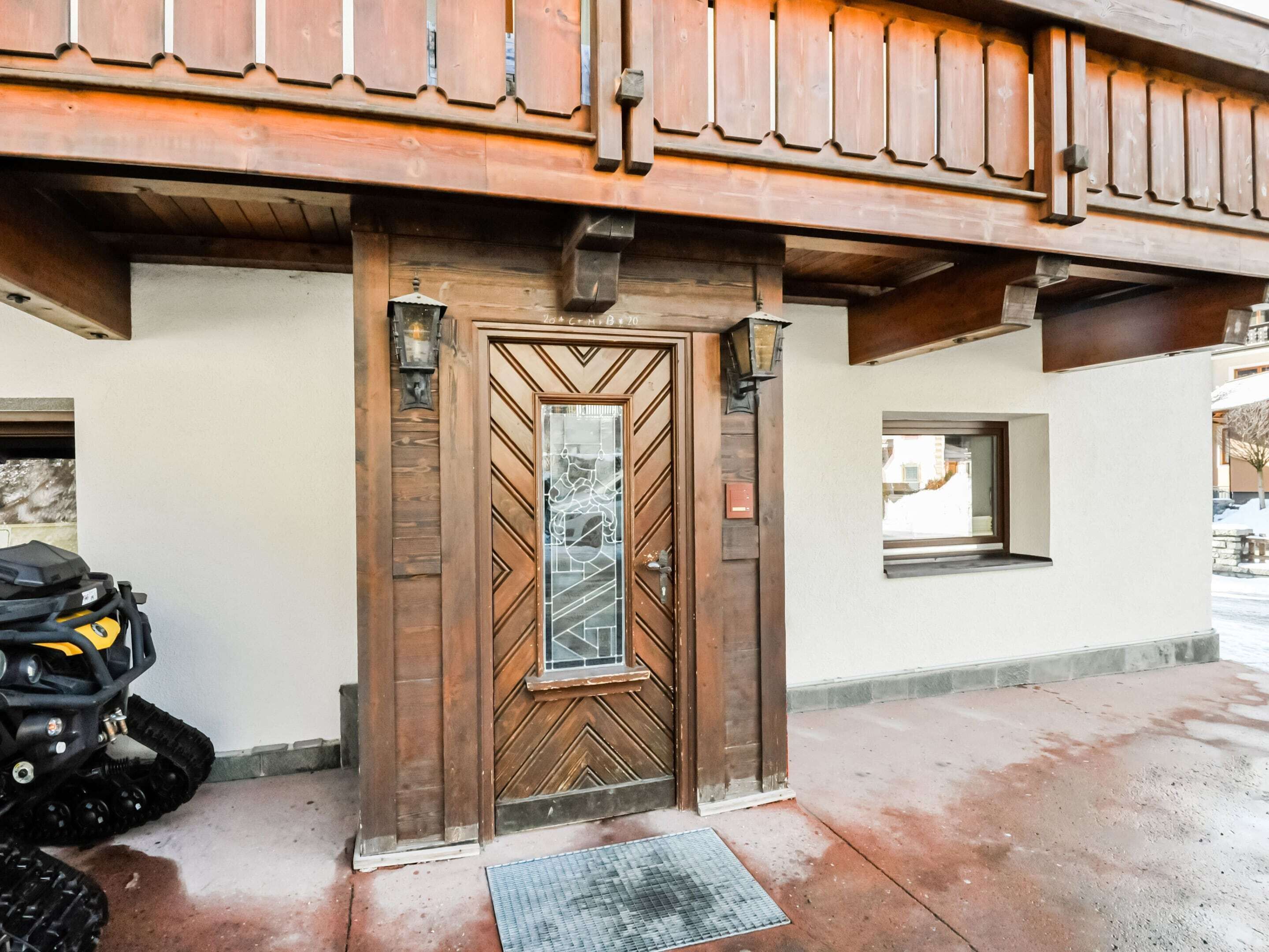 A wooden door with a geometric pattern, a small window, and a motorcycle parked outside.