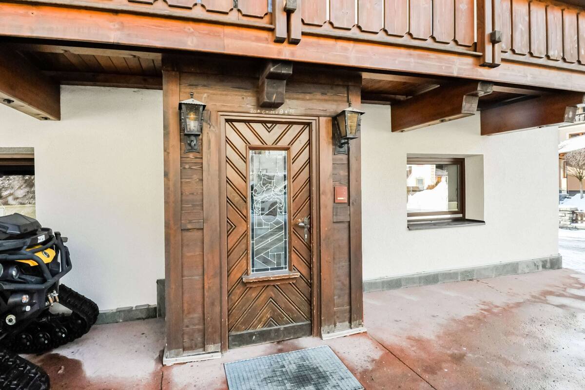 A wooden door with a geometric pattern, a small window, and a motorcycle parked outside.