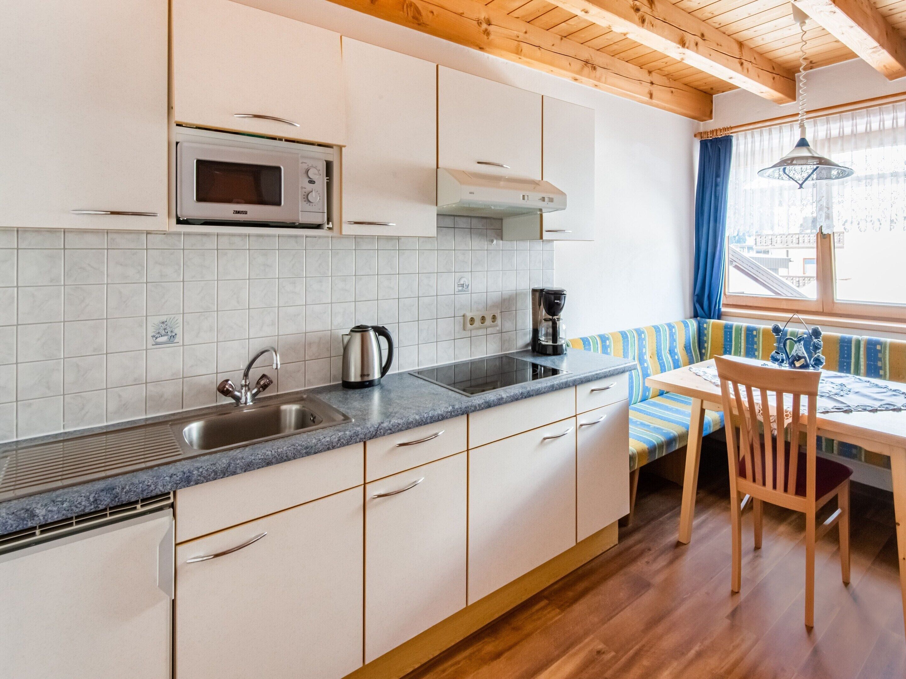 Una cocina con armarios blancos, microondas, cafetera y ventana con vistas a la ciudad.