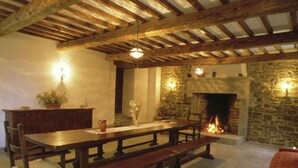 A rustic dining area with a long wooden table, benches, and a stone fireplace. - Farmhouse in Apecchio With Swimming Pool, Terrace, Garden (Apecchio)