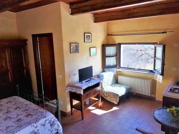 A bedroom with a bed, a desk, a chair, a radiator, and a window with a view of trees. - Farmhouse in Apecchio With Swimming Pool, Terrace, Garden (Apecchio)