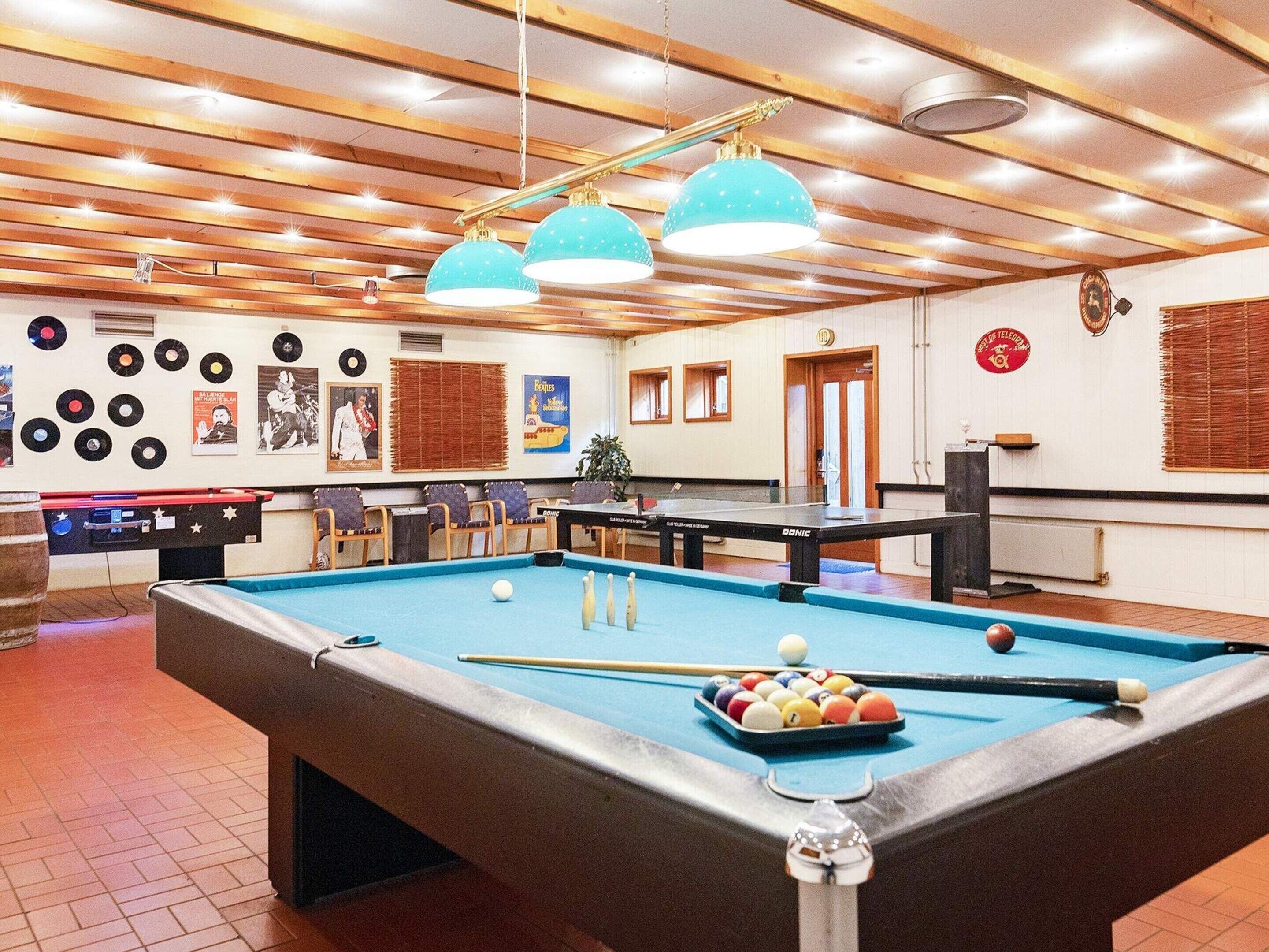 A pool table with balls, a foosball table, and a jukebox.