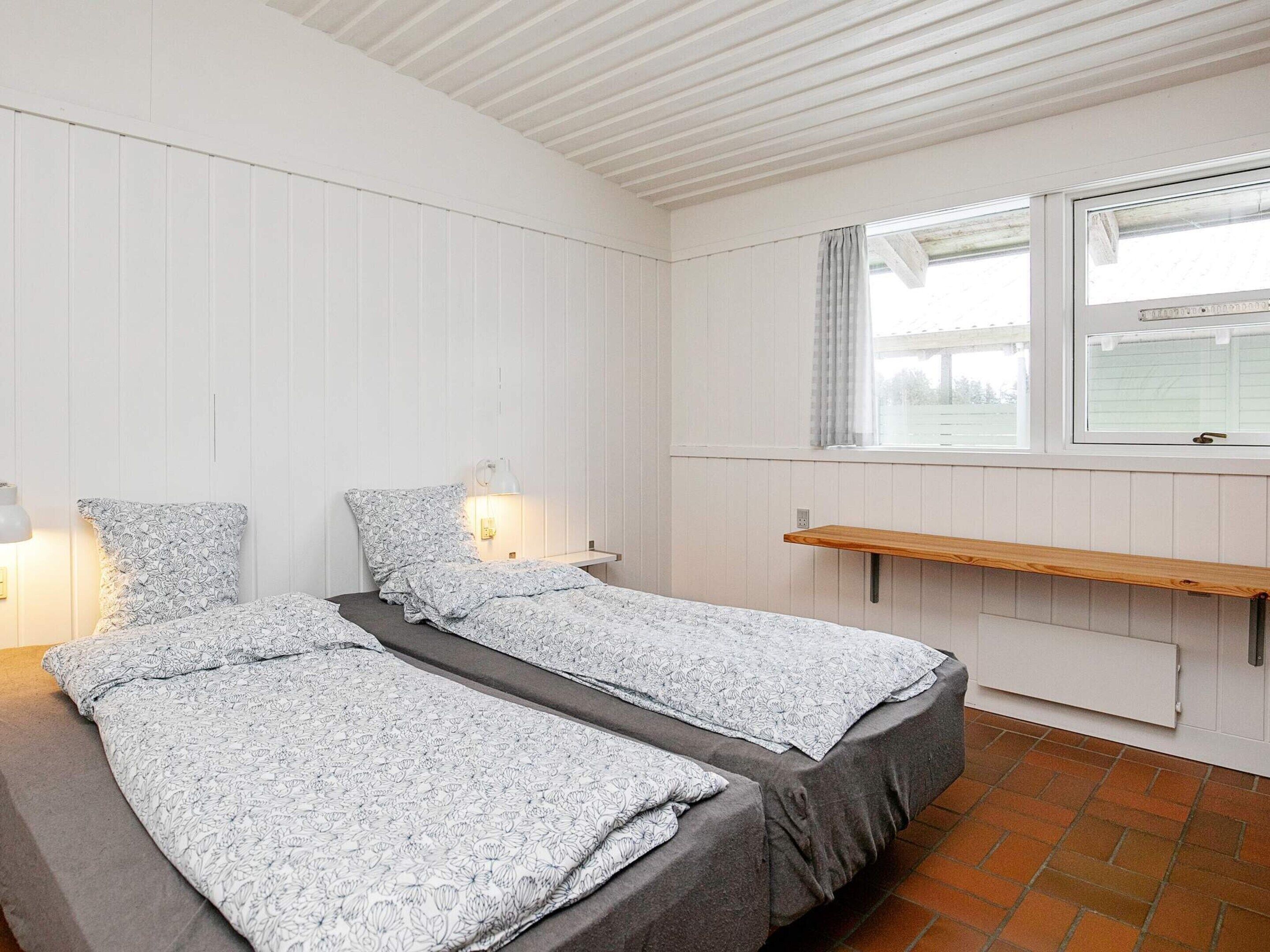 Un dormitorio con dos camas, una ventana, un estante y una lámpara.