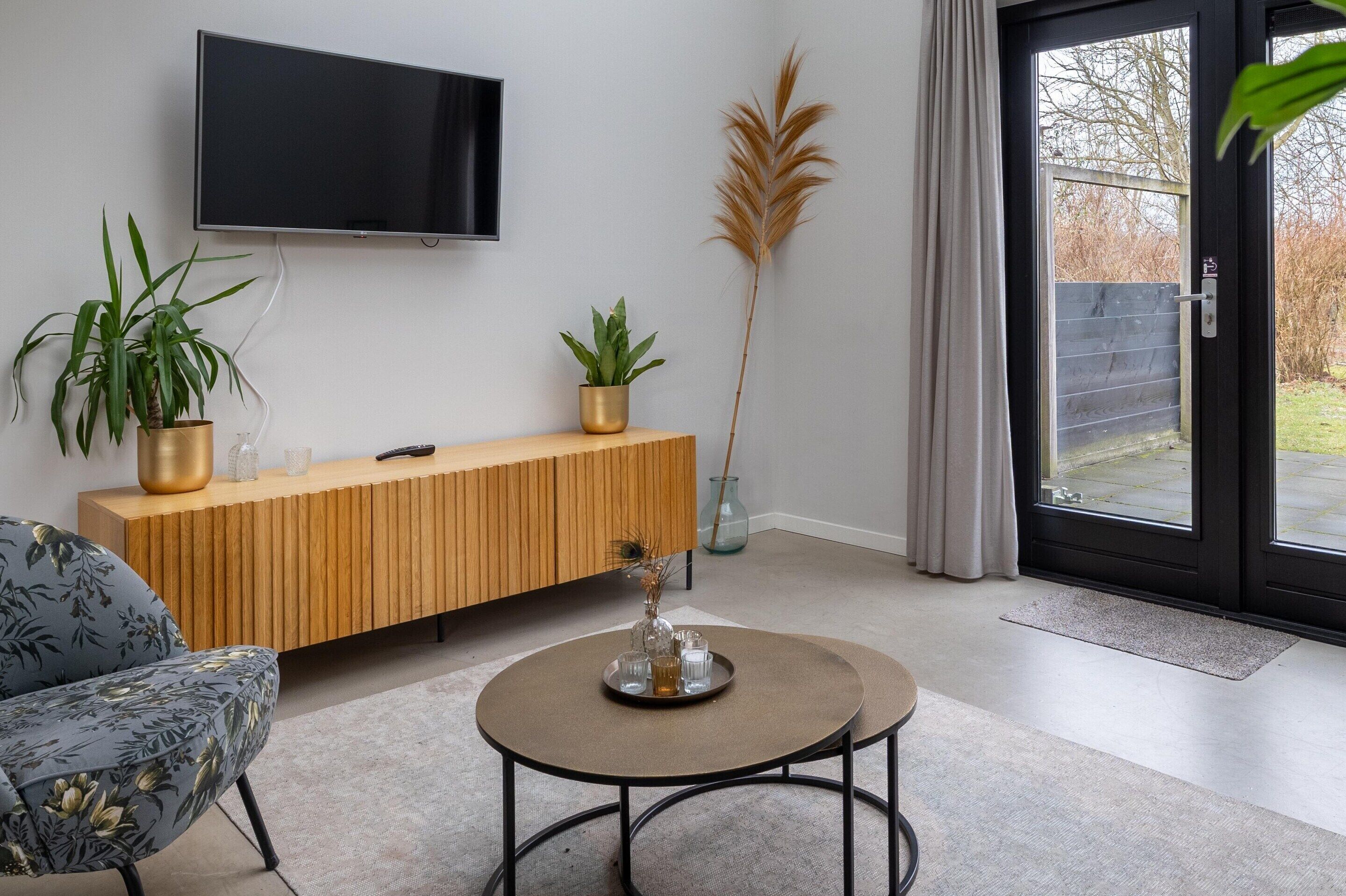 A modern living room with a wooden console, a round coffee table, and two potted plants.