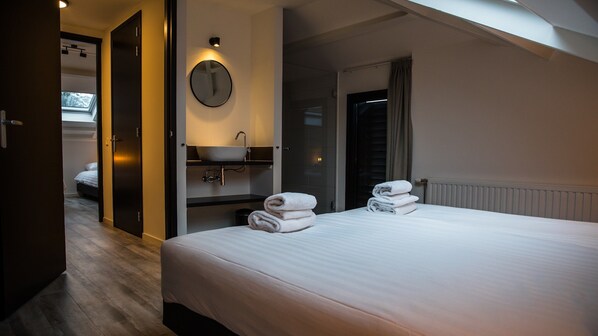 A hotel room with a bed, a round mirror, a sink, and a window.
