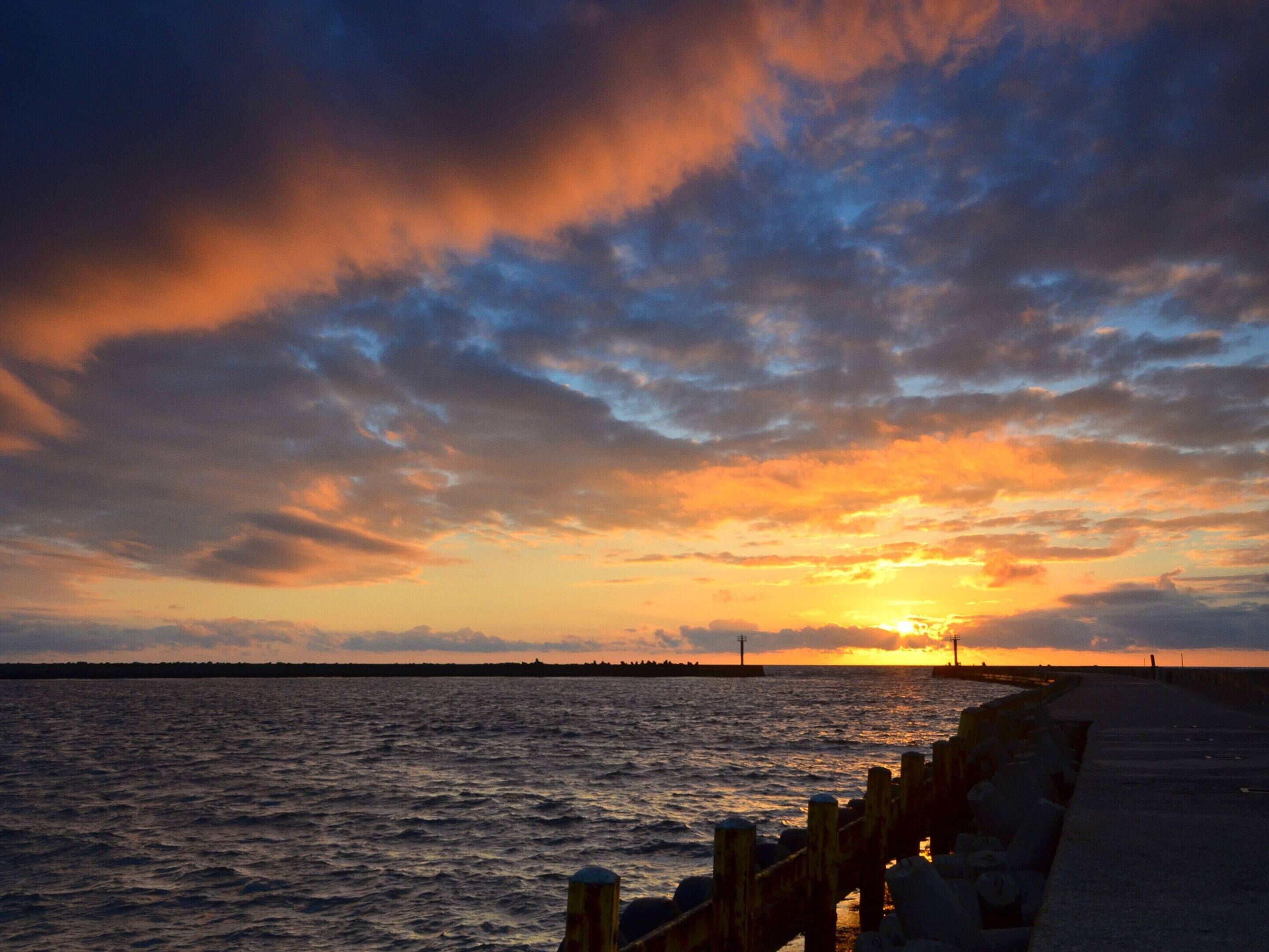 Ein Sonnenuntergang über einem Gewässer mit einer anlegenden Pier.