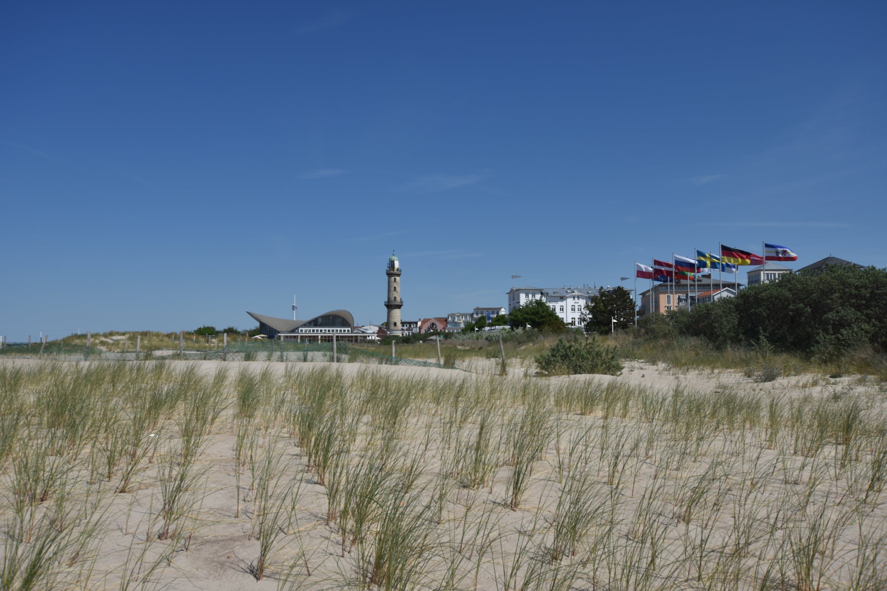A coastal area with a lighthouse, buildings, and flags.