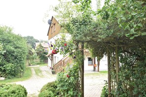 Een tuinpad dat leidt naar een gebouw met een houten trap.