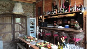 A rustic bar area with wooden beams, a brick wall, and a variety of bottles and glasses. - Holiday Home in West Flanders With Garden and Bubble Bath (Pittem)