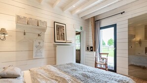 A bedroom with a bed, a chair, a radiator, and a door leading to a balcony. - Holiday Home in West Flanders With Garden and Bubble Bath (Pittem)