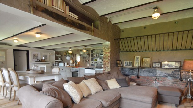 A spacious living area with a large sectional sofa, a dining table, and a kitchen in the background. - Holiday Home in West Flanders With Garden and Bubble Bath (Pittem)
