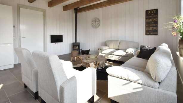 A cozy living room with a fireplace, a clock, and a motivational quote on the wall. - Studio Hazenborgh in Callantsoog Near the sea (Callantsoog)