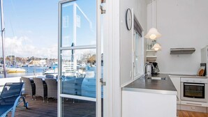 Una cocina moderna con vista a un puerto deportivo, un comedor con asientos exteriores y un amplio ventanal.