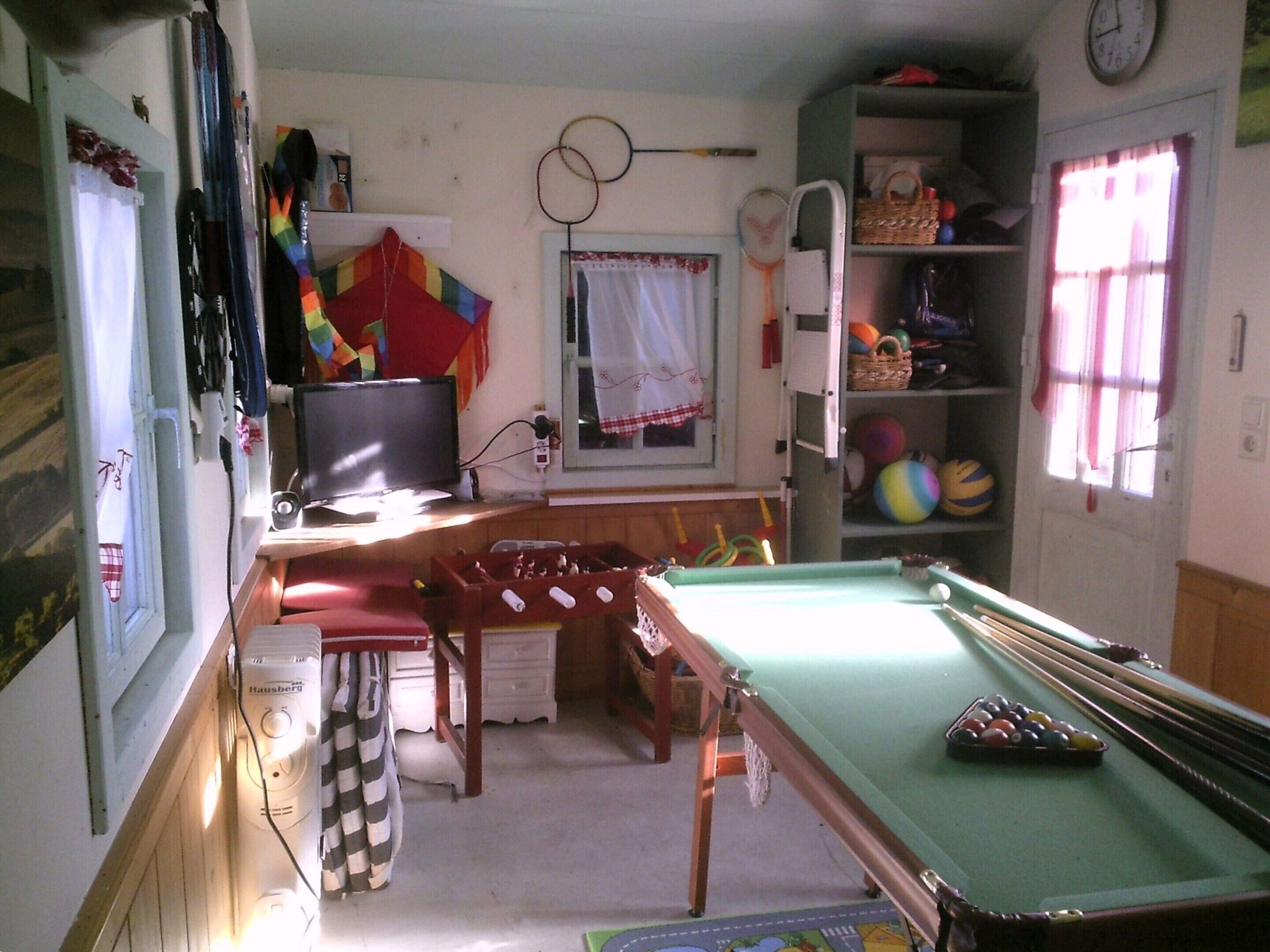 Une pièce équipée d’une table de billard, d’un téléviseur et de divers équipements de sport.