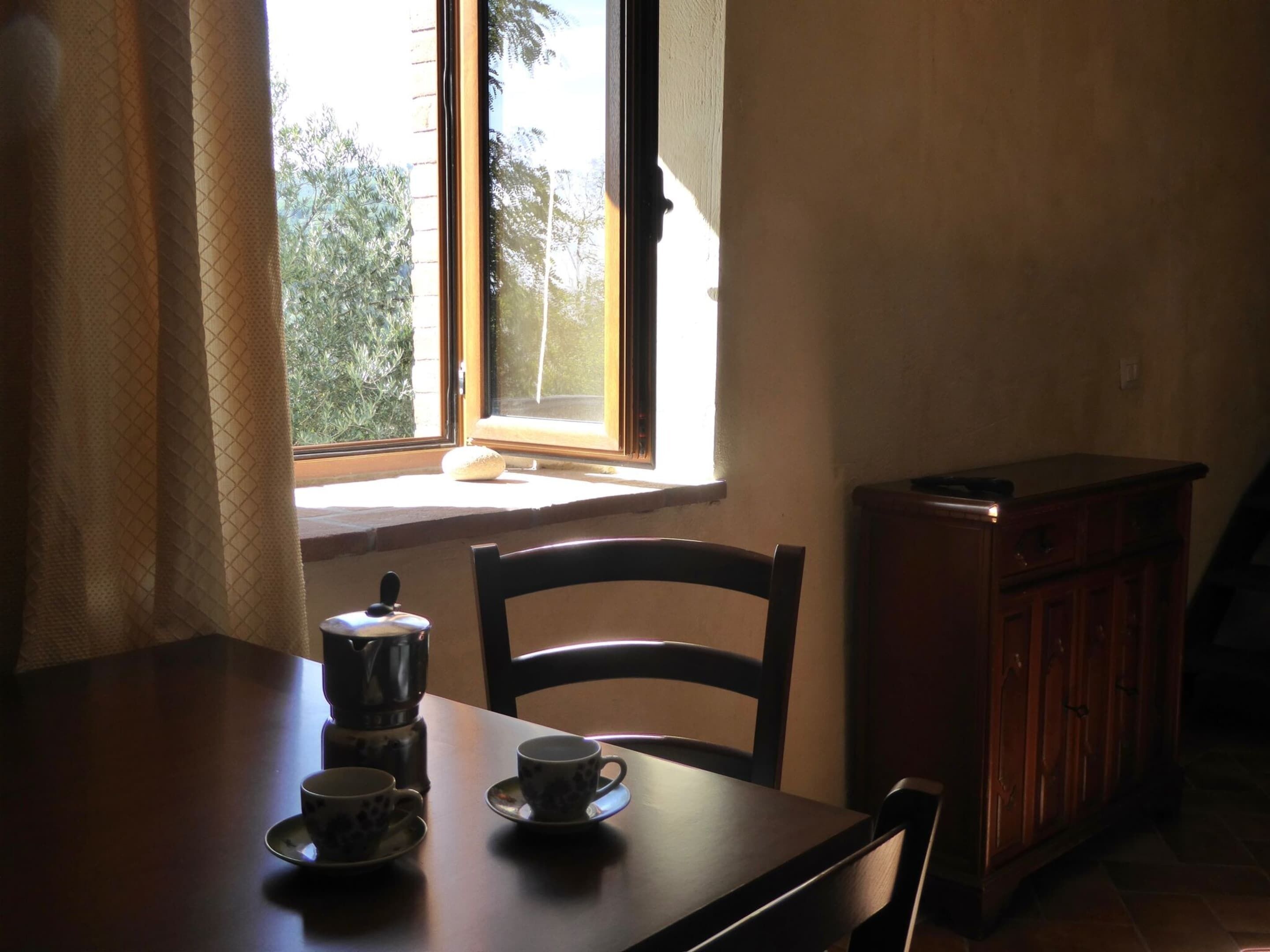 Un espace repas comprenant une table, des chaises et une fenêtre donnant sur la forêt.