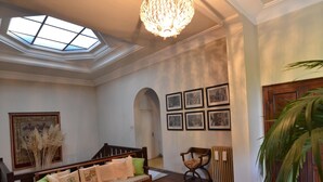 A room with a wooden bench, a chandelier, a skylight, and framed pictures on the wall.