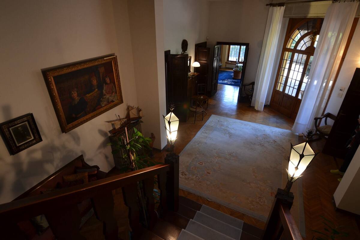 A staircase with a wooden handrail, a patterned rug, and wall-mounted lamps.