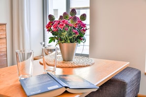 Una mesa con una maceta de flores, dos vasos y un libro.