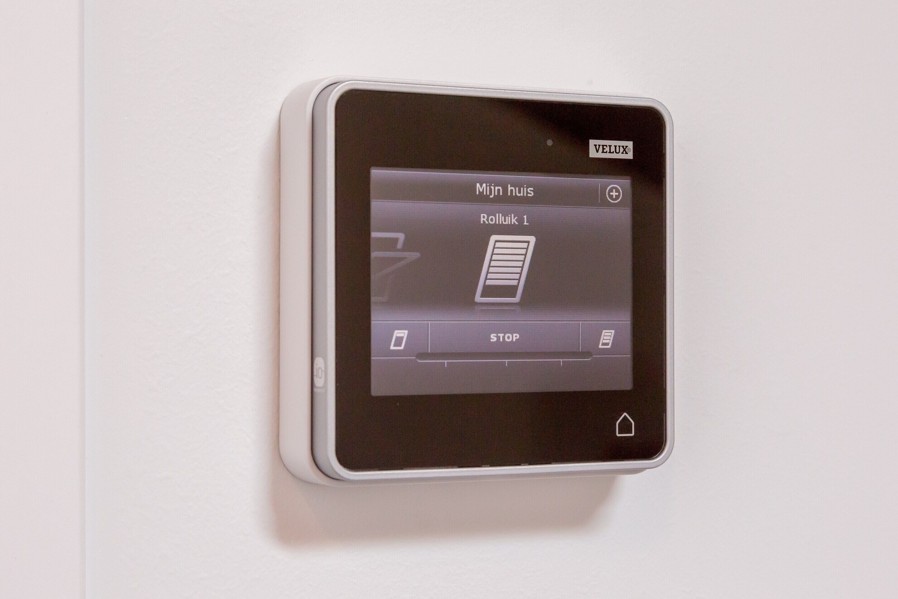 A Velux smart window control panel with a display showing "Mijn huis" and "Rolliek 1".