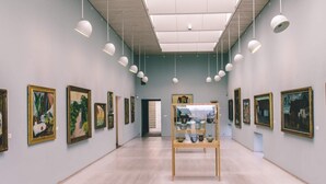 An art gallery with paintings on the walls and a central display case. - 6 Person Holiday Home in Allinge (Gudhjem)