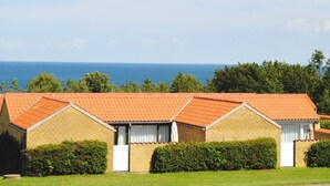 A row of brick buildings with orange tiled roofs, white window frames, and a view of the sea. - 4 Person Holiday Home in Allinge (Allinge)
