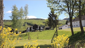 Un paysage rural avec une grande grange, un bâtiment blanc et une colline verdoyante.