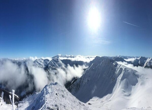 A snow-covered mountain landscape with a clear sky and a bright sun.