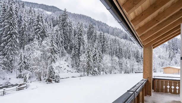A wooden balcony with a view of a snow-covered forest and mountains. - Luxury Chalet in Saalbach-hinterglemm With Sauna (Saalbach-Hinterglemm)