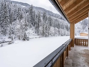 A wooden balcony with a view of a snow-covered forest and mountains. - Luxury Chalet in Saalbach-hinterglemm With Sauna (Saalbach-Hinterglemm)