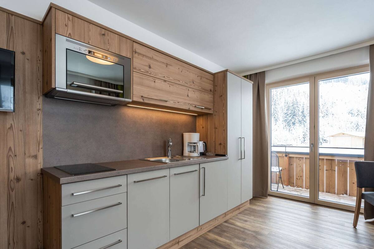 A modern kitchen with wooden cabinetry, a built-in oven, and a coffee maker.
