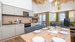 A modern kitchen with white cabinets, a wooden countertop, and a dining area set for six with a wooden table. - Luxury Chalet in Saalbach-hinterglemm With Sauna (Saalbach-Hinterglemm)