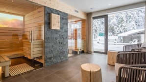 A modern spa area with wooden walls, a stone accent wall, and a glass door leading outside. - Luxury Chalet in Saalbach-hinterglemm With Sauna (Saalbach-Hinterglemm)