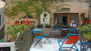 An outdoor seating area with blue and orange chairs, a sign for 'IL GELATO DI CHIAR', and red flowers. - Idyllic Farmhouse in Gambassi Terme-fi With Swimming Pool (Gambassi Terme)