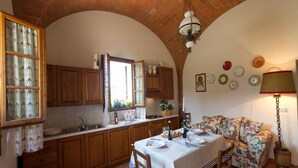 A cozy kitchen with wooden cabinets, a dining table set for four, and a floral sofa. - Idyllic Farmhouse in Gambassi Terme-fi With Swimming Pool (Gambassi Terme)