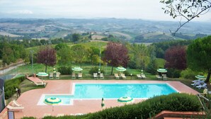 A swimming pool with sun loungers and umbrellas, surrounded by well-maintained hedges and trees, with a view of rolling hills in the background. - Idyllic Farmhouse in Gambassi Terme-fi With Swimming Pool (Gambassi Terme)