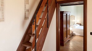 A wooden staircase leading to a bedroom with a bed and nightstand. - Pleasant Apartment in Santa Maria Degli Angeli With Pool (Assisi)
