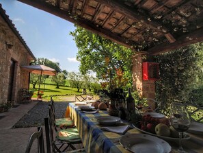 An outdoor dining area with a table set for two, surrounded by greenery and a brick building. - Cosy Farmhouse in Proceno With Swimming Pool (Proceno)