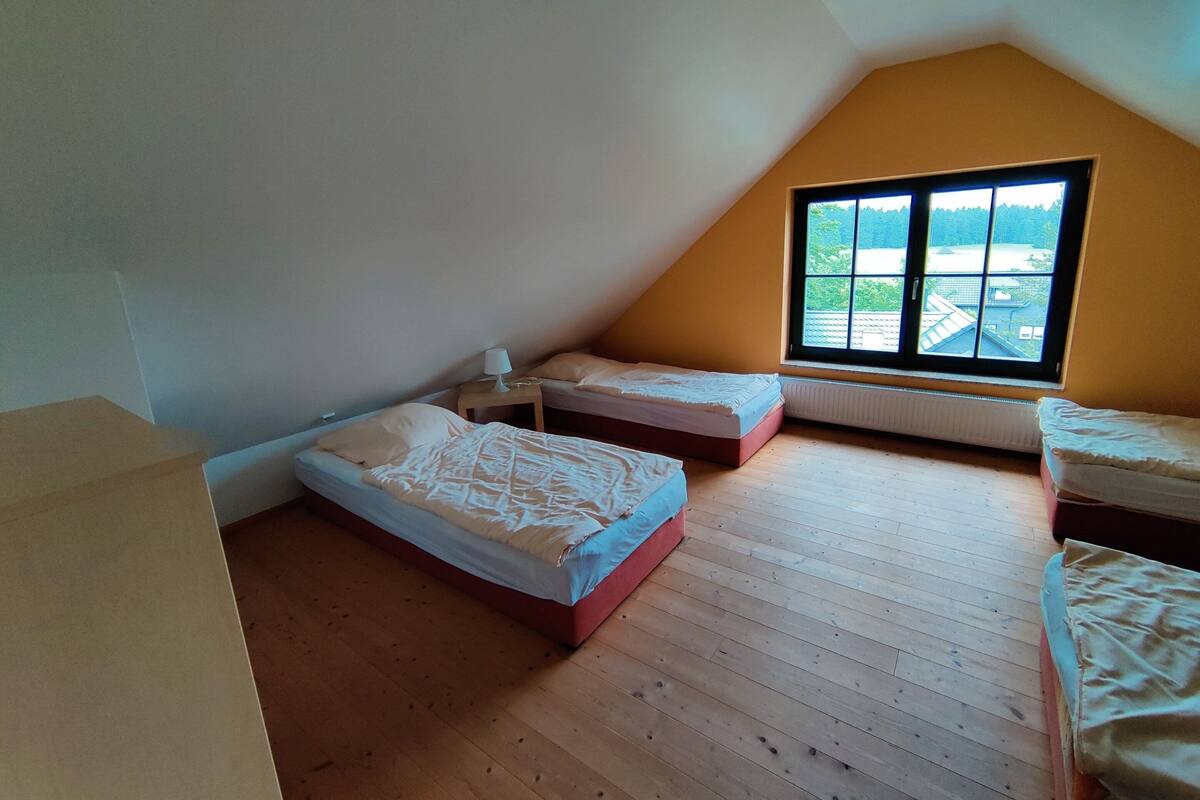 A small, triangular attic bedroom with two beds, a window, and a radiator.