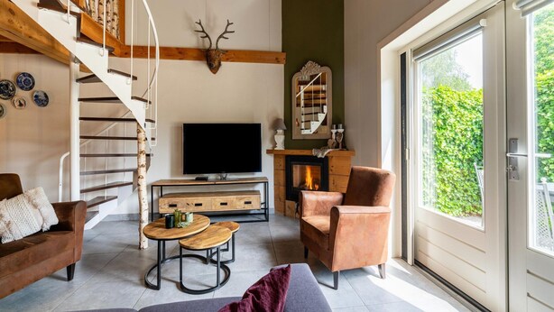 Una sala moderna con chimenea, televisor y escalera con barandilla de madera.